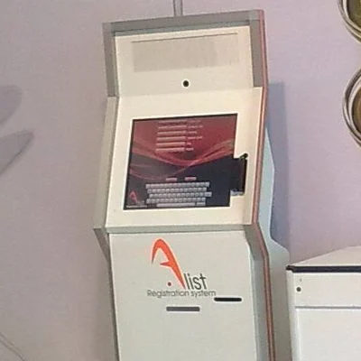 An ALIST self-service station: a touch screen in a standing enclosure carrying the system logo