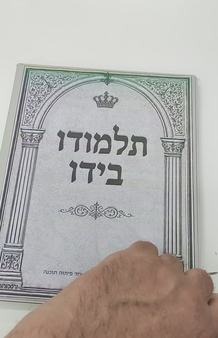 המכשיר של תלמודו בידו, מציג את שער הספר על מסך דיו אלקטרוני