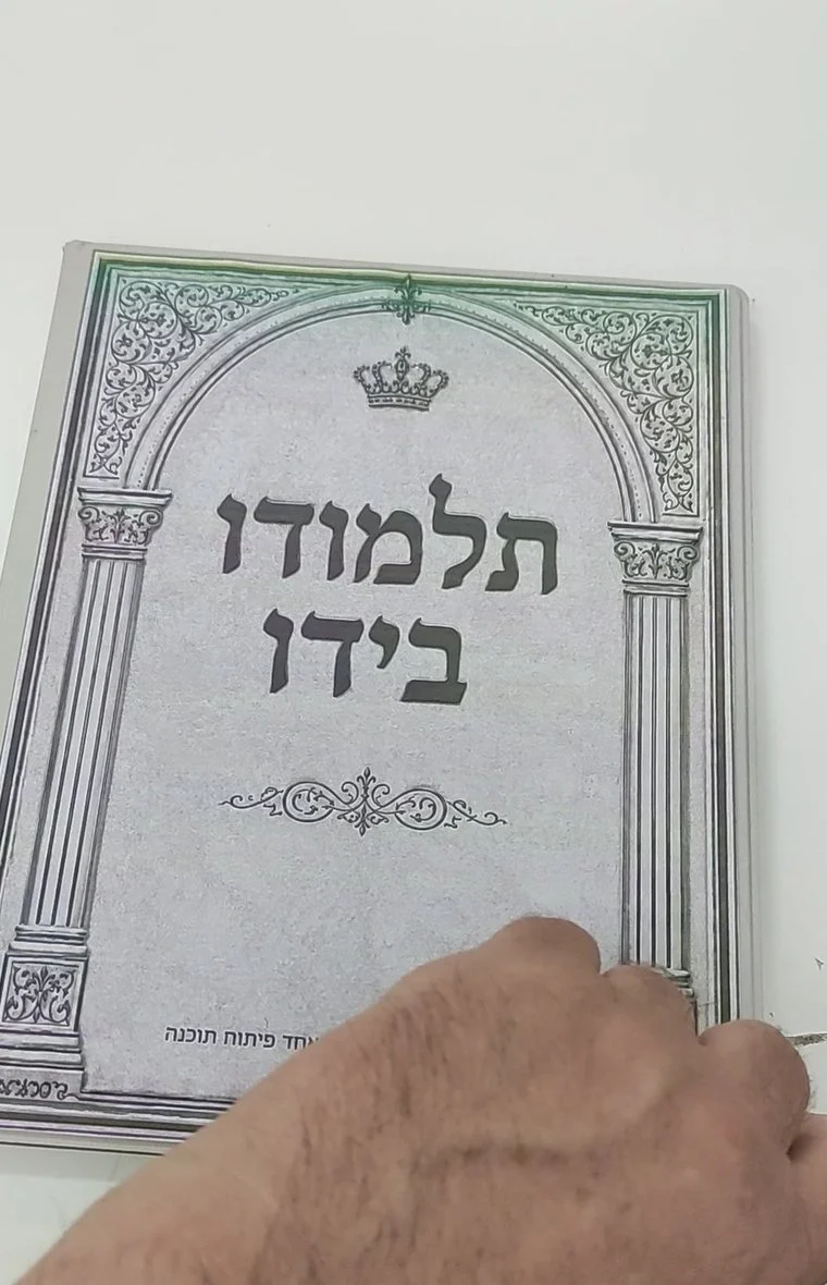 המכשיר של תלמודו בידו, מציג את שער הספר על מסך דיו אלקטרוני